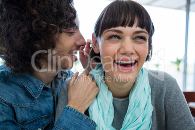 Man whispering in woman s ear
