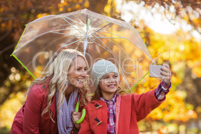 Girl taking selfie with mother at park