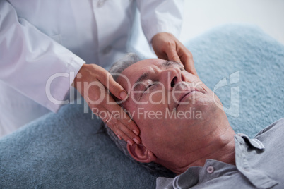 Senior man receiving head massage from physiotherapist