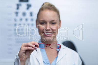 Smiling female optometrist holding spectacles