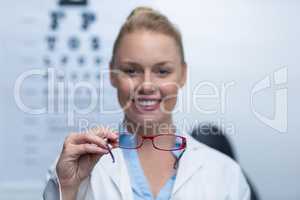 Smiling female optometrist holding spectacles