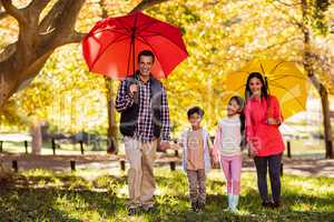 Happy family walking with umbrellas at park