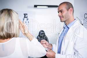 Male optometrist taking eye test of female patient