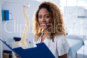 Smiling physiotherapist holding clipboard in clinic