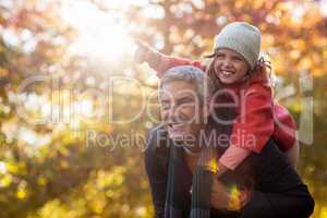 Father piggybacking daughter against autumn trees