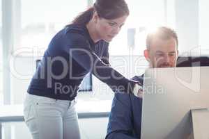 Teacher assisting mature student in computer room