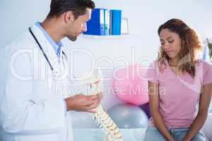 Physiotherapist explaining spine model to patient