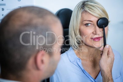 Optometrist examining female patient with medical equipment