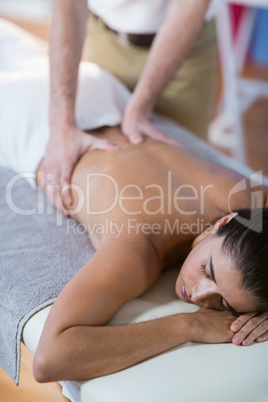 Male physiotherapist giving back massage to female patient