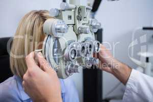 Female patient under going eye test through phoropter