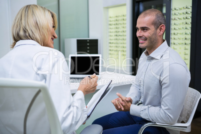 Female optometrist talking to male patient