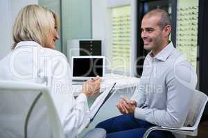 Female optometrist talking to male patient