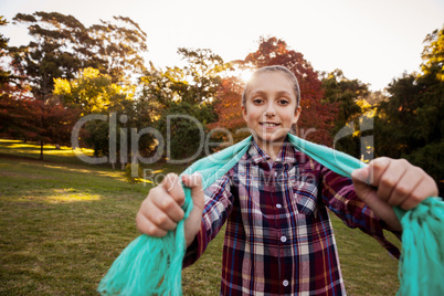 Portrait of happy girl showing scarf while standing in park