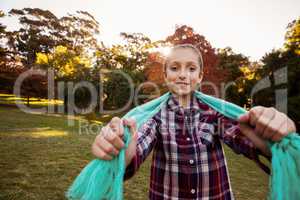 Portrait of happy girl showing scarf while standing in park