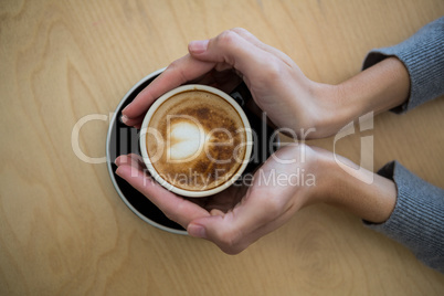 Woman holding cup of coffee on table