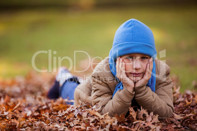 Portrait of cute boy lying at park during autumn