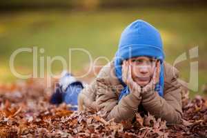 Portrait of cute boy lying at park during autumn