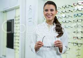 Smiling optometrist holding spectacles in optical store