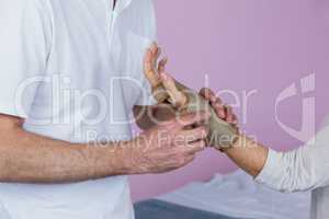 Mid section of physiotherapist examining a senior womans wrist