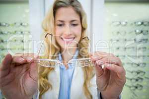 Smiling female optometrist holding spectacles