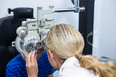 Female optometrist examining young patient on phoropter