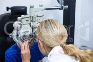 Female optometrist examining young patient on phoropter