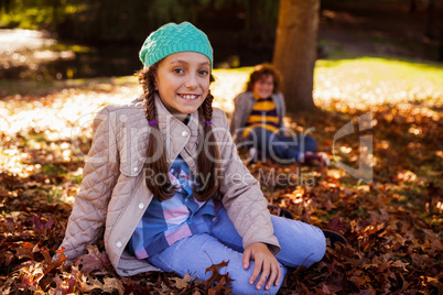 Portrait of smiling siblings sitting at park during autumn