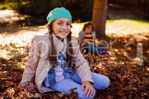 Portrait of smiling siblings sitting at park during autumn