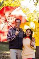 Portrait of smiling couple with umbrellas