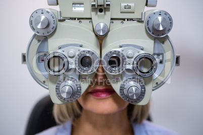 Female patient looking through phoropter during eye examination