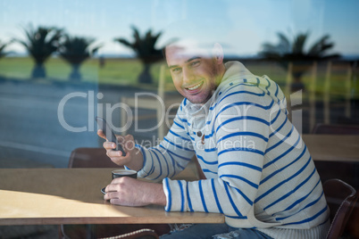 Smiling man using mobile phone in the coffee shop