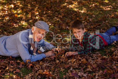 Grandfather and grandson lying on autumn leaves