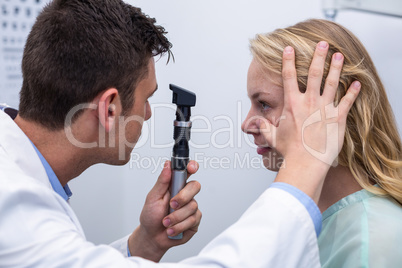 Optometrist examining female patient through ophthalmoscope