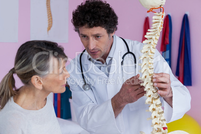 Physiotherapist explaining the spine model to patient