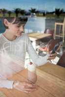 Woman using mobile phone while having milkshake