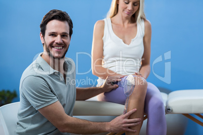 Physiotherapist examining female patients knee with goniometer