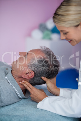 Senior man receiving neck massage from physiotherapist