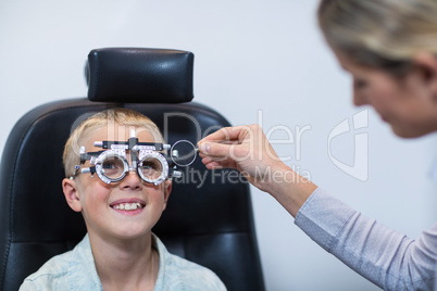 Female optometrist examining young patient with phoropter