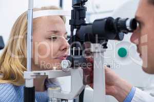 Optometrist examining female patient on slit lamp