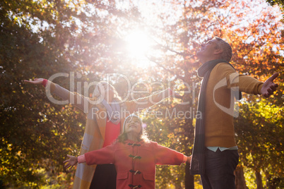 Family with arms outstretched against trees