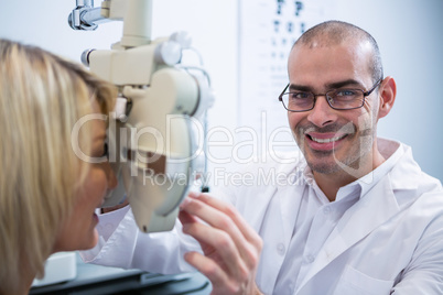 Smiling optometrist examining female patient on phoropter