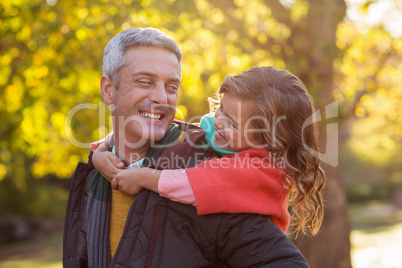 Happy father piggybacking daughter at park