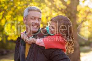 Happy father piggybacking daughter at park