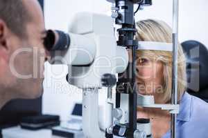 Optometrist examining female patient on slit lamp