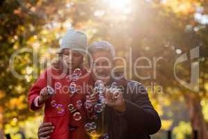 Father and daughter playing with bubbles at park