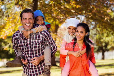 Parents piggybacking children at park