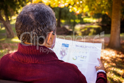Man reading newspaper while relaxing on bench