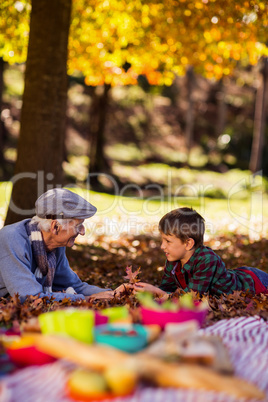 Grandfather and grandson lying on field during autumn