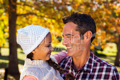 Smiling father carrying daughter at park