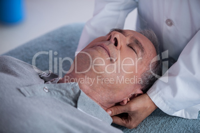 Senior man receiving neck massage from physiotherapist